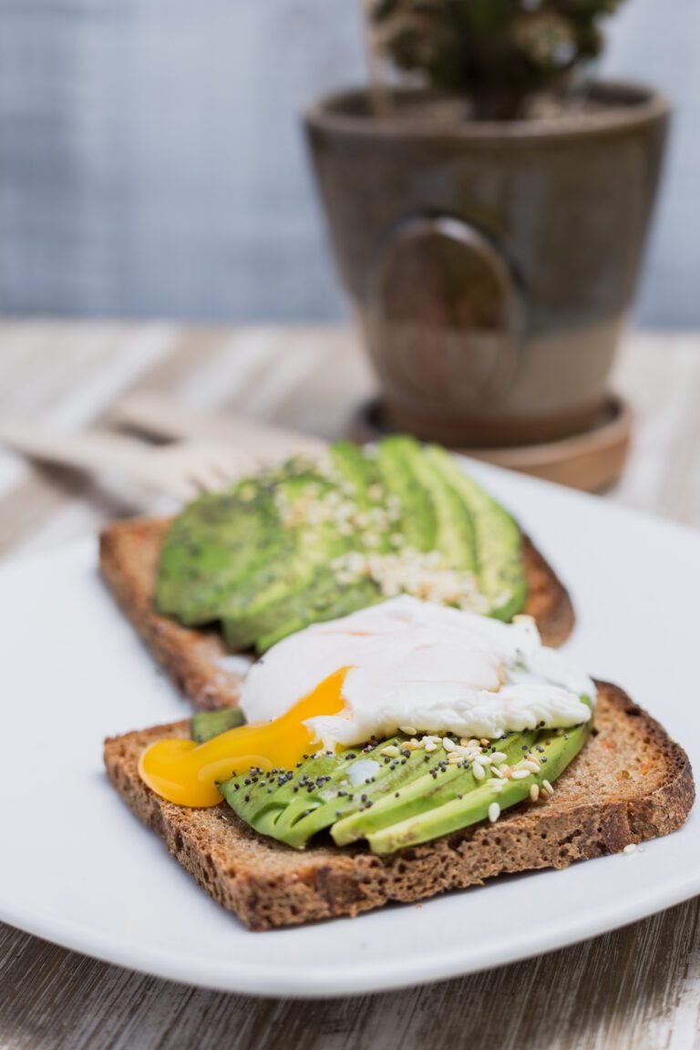 Two toasts with avocado and egg on a wooden table