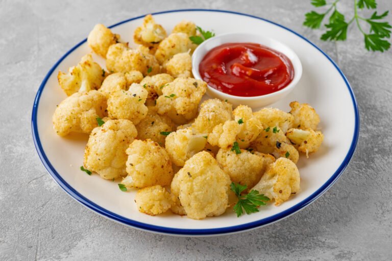 Baked cauliflower with parmesan cheese on a gray concrete background. Vegetarian healthy food