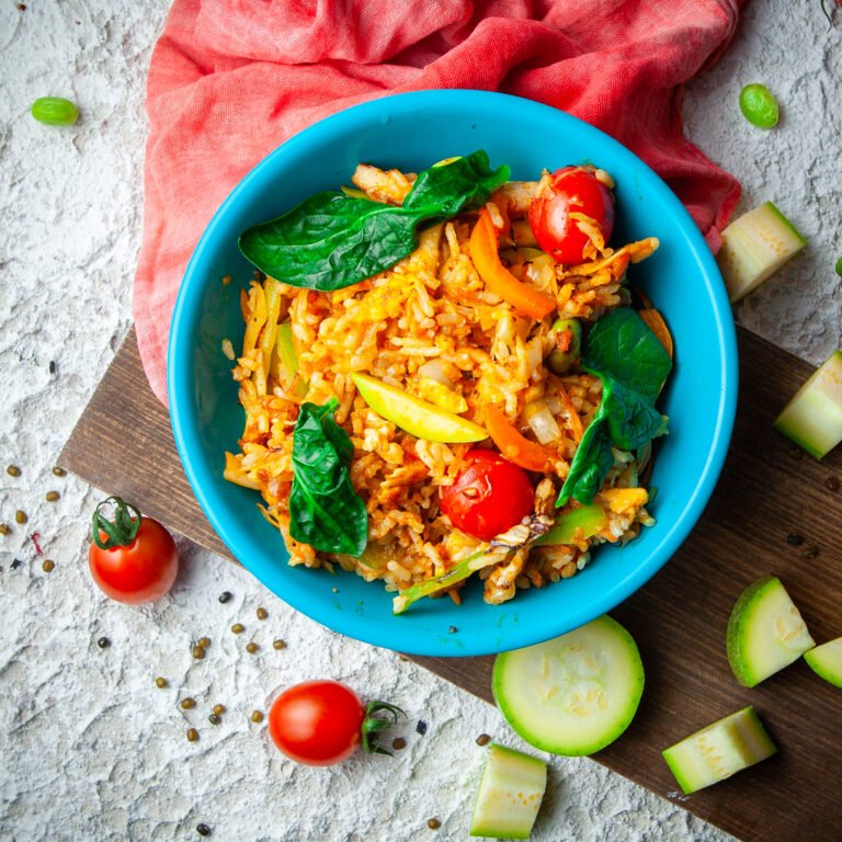 Delicious meal in a blue plate on a wood, red cloth and white textured background. top view