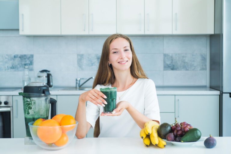 A glass of detox drinks on a woman's hand with a healthy smile