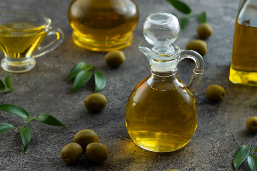 Some olive on the floor and a designed jar full of olive oil