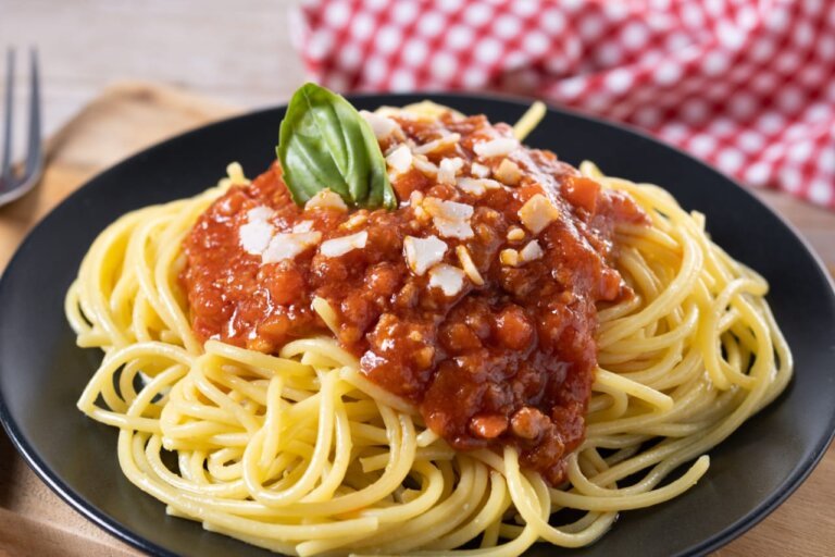 Spaghetti Bolognese is served in a plate on a dinning table